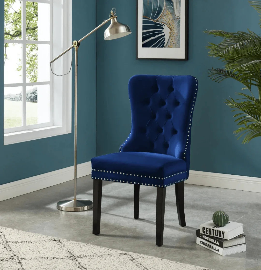 Navy blue velvet tufted accent chair with nailhead trim in a modern living room