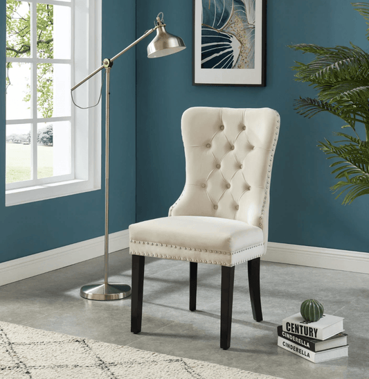 Cream tufted accent chair with nailhead trim beside a silver floor lamp in a blue room