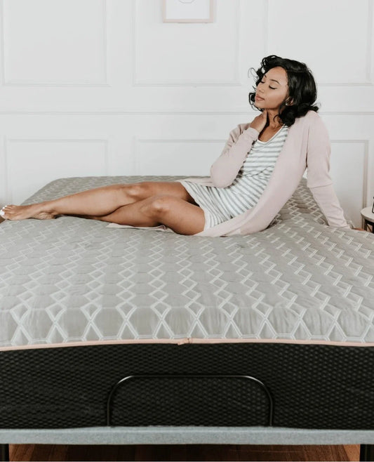 Woman relaxing on a grey quilted mattress topper on a bed